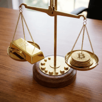 Golden balance scale weighing a gold bar against a stack of Bitcoin coins.